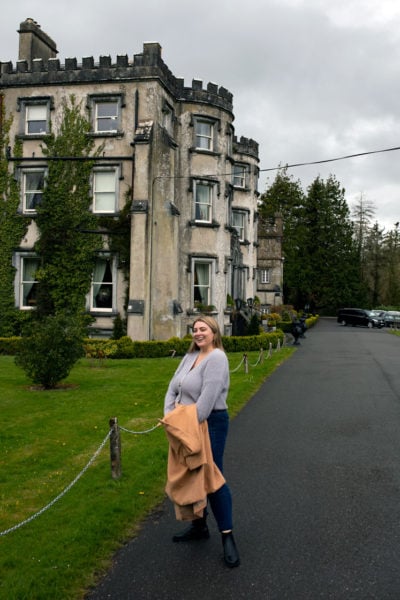 woman traveler standing in front of an old Ireland castle hotel near Kerry